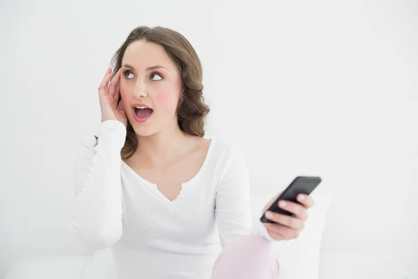 Chockad kvinna med mobiltelefon tittar bort — Stockfoto