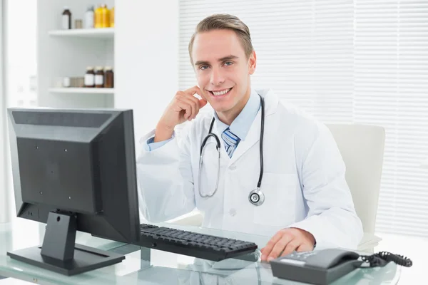 Confident doctor sitting with computer at medical office — Stock Photo, Image