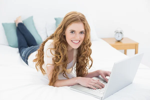 Sorrindo loiro casual usando laptop na cama — Fotografia de Stock