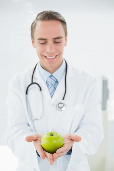 Smiling male doctor holding a green apple — Stock Photo, Image