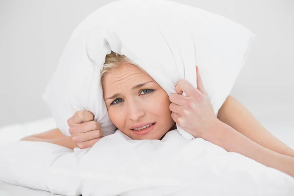 Mulher descontente cobrindo orelhas com travesseiro — Fotografia de Stock