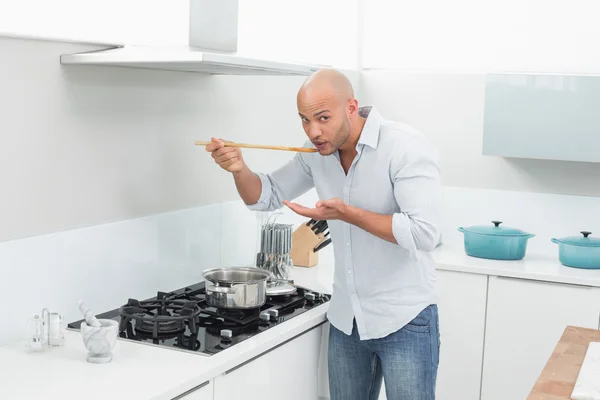 Άνθρωπος γευσιγνωσία τροφίμων ενώ ετοιμάζει στην κουζίνα — Φωτογραφία Αρχείου