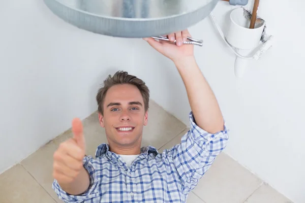 Technician gesturing thumbs up under hot water heater — Stock Photo, Image