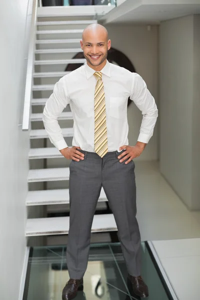 Smiling businessman standing against staircase — Stock Photo, Image