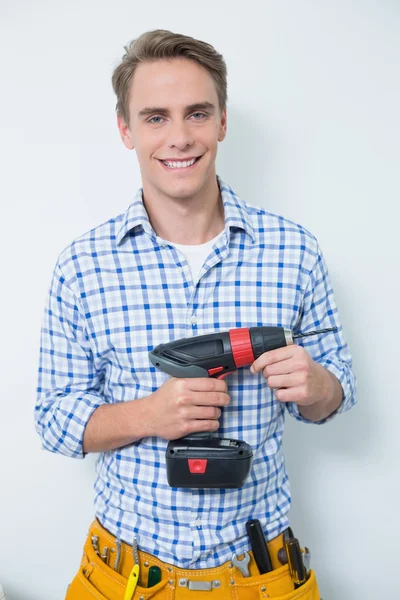 Portrait of a smiling handsome young handyman holding drill — Stock Photo, Image