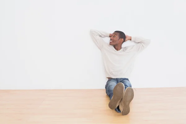 Lässiger Afro-Mann auf dem Boden sitzend, während er zur Wand hinaufblickt — Stockfoto
