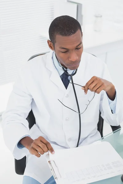 Concentrated doctor reading a note at medical office — Stock Photo, Image