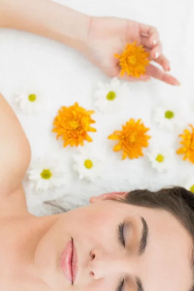 Hermosa mujer con los ojos cerrados y flores en salón de belleza — Foto de Stock