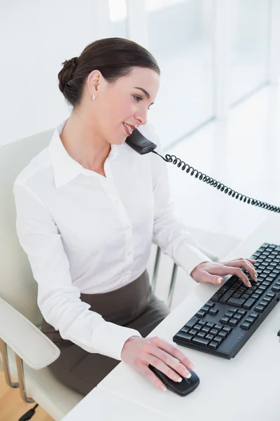 Donna d'affari concentrata che utilizza computer e telefono — Foto Stock