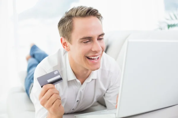Cheerful casual young man doing online shopping on sofa — Stock Photo, Image
