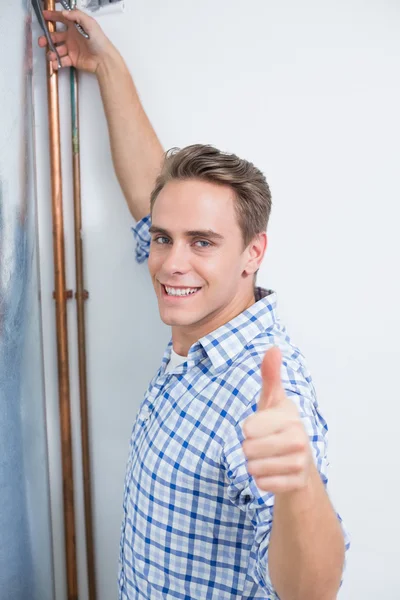 Technician gesturing thumbs up by hot water heater — Stock Photo, Image