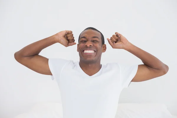 Afro uomo svegliarsi a letto e allungare le braccia — Foto Stock
