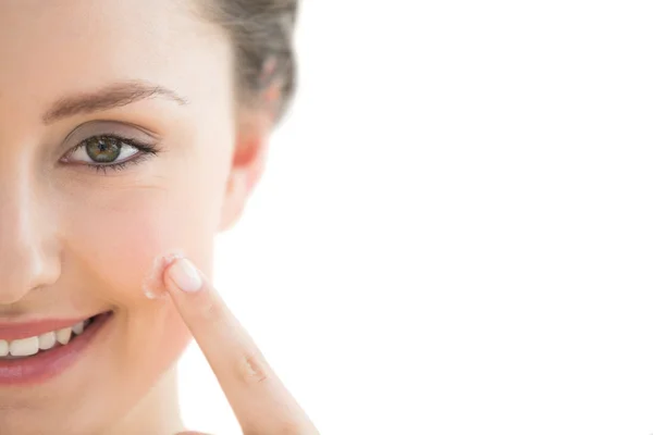 Beautiful young woman applying cream to her face — Stock Photo, Image