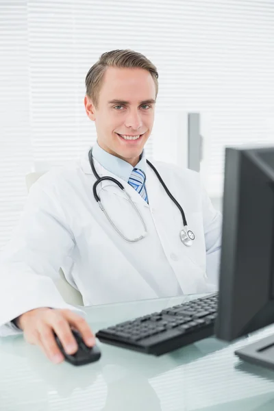 男性医師の診療所でコンピューターと笑みを浮かべてください。 — ストック写真