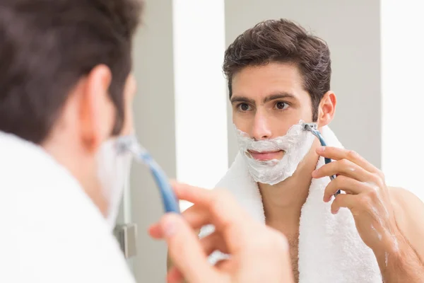 Bello giovane uomo con riflesso rasatura in bagno — Foto Stock