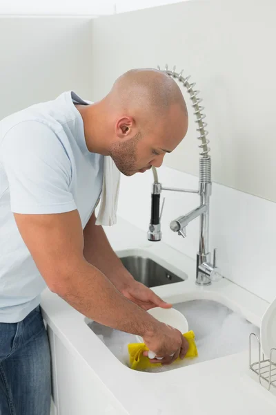 Junger Mann beim Geschirrspülen in der Küche — Stockfoto