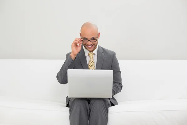 Empresário usando laptop no sofá em casa — Fotografia de Stock