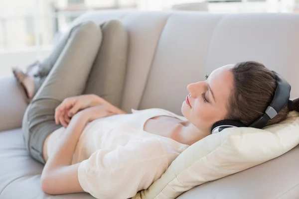 轻松休闲的年轻女子坐在沙发上的音乐欣赏 — 图库照片