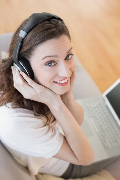随便的女人，同时享受音乐在家里使用便携式计算机 — 图库照片