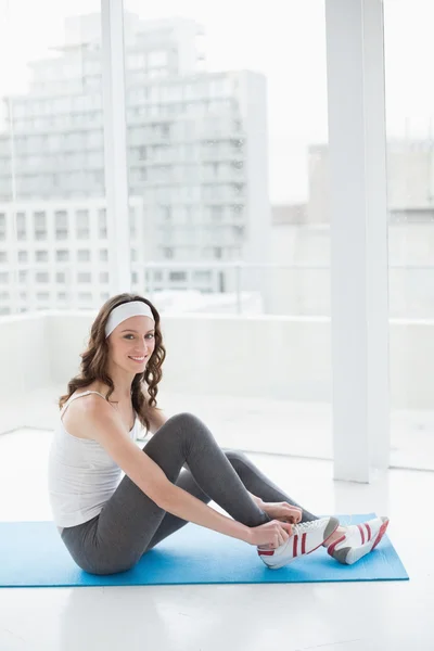 Toned woman wearing shoes on exercise mat at fitness studio — Stock Photo, Image