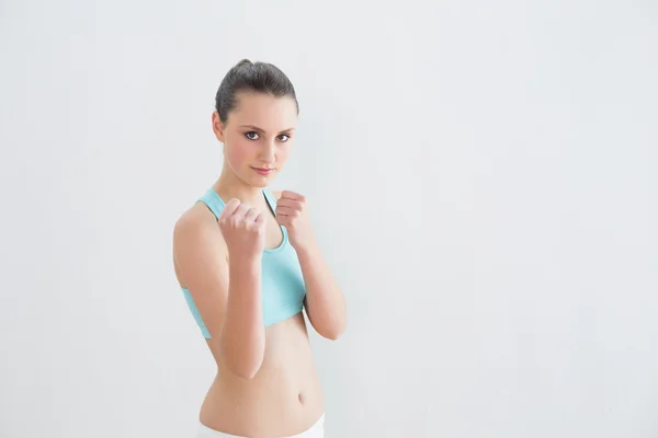 Smiling fit woman clenching fists against wall — Stock Photo, Image