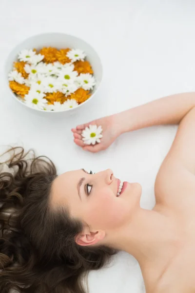 Beautiful woman lying with bowl of flowers in beauty salon — Stock Photo, Image