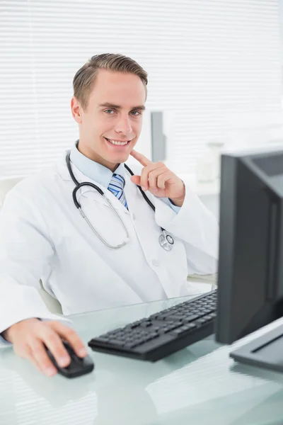 Sorrindo médico masculino com computador no consultório médico — Fotografia de Stock