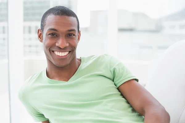 Χαμογελώντας χαλαρή Αφρο άνθρωπος που κάθεται στον καναπέ — Φωτογραφία Αρχείου
