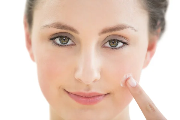 Bella giovane donna che applica la crema sul suo viso — Foto Stock