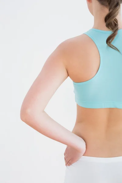 Achteraanzicht van afgezwakt vrouw met hand op heup tegen muur — Stockfoto