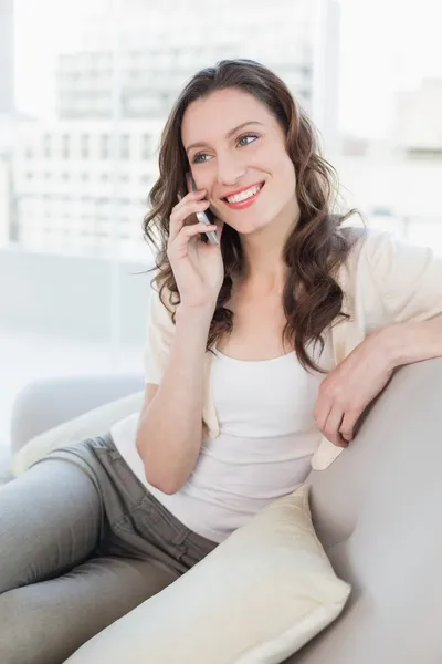 Ontspannen jonge vrouw met behulp van mobiele telefoon op sofa — Stockfoto