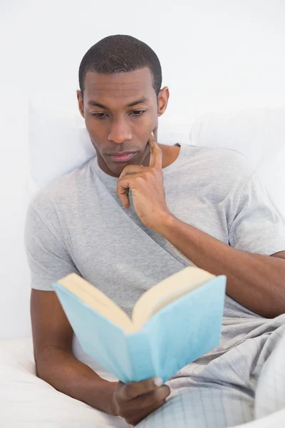 Rilassato afro uomo lettura libro a letto — Foto Stock