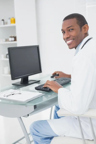 Médico sorrindo usando o computador no consultório médico — Fotografia de Stock