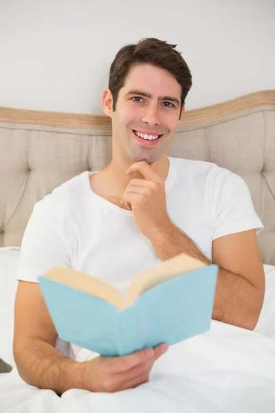 Porträt eines entspannten jungen Mannes, der Buch im Bett liest — Stockfoto