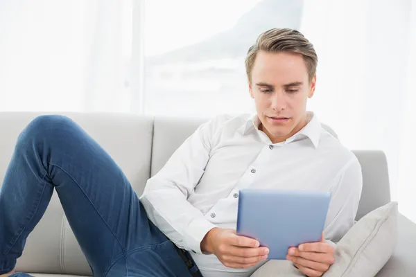 Casual genç adam kanepede dijital tablet kullanma — Stok fotoğraf