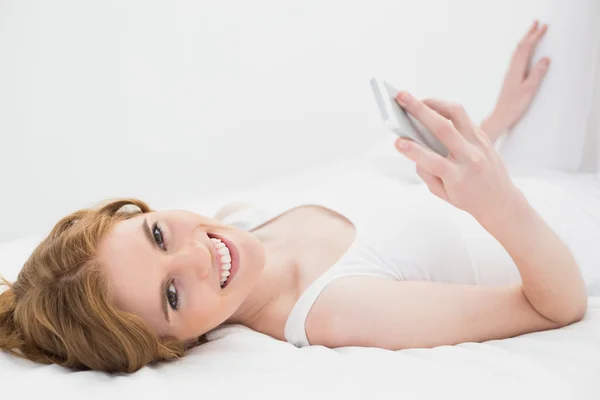 Retrato de mulher relaxada com telefone celular na cama — Fotografia de Stock