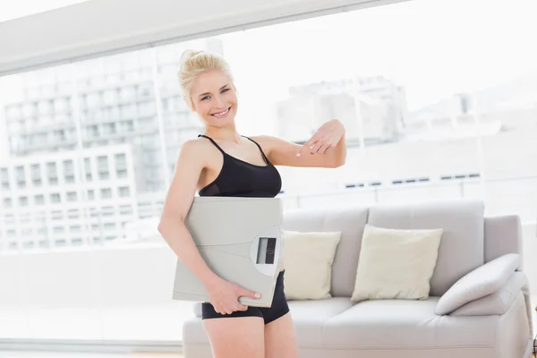 Woman in sportswear carrying scale in fitness studio — Stock Photo, Image