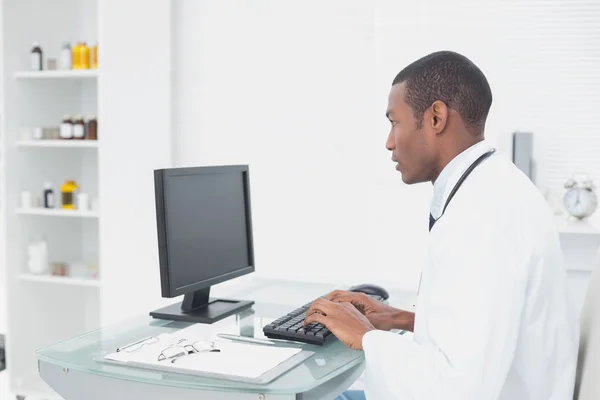 หมอที่มุ่งเน้นการใช้คอมพิวเตอร์ที่ออฟฟิศแพทย์ — ภาพถ่ายสต็อก