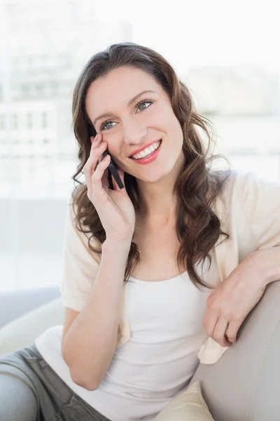 Relaxed woman using cellphone while sitting on sofa — Stock Photo, Image