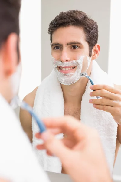 Красивый молодой человек с отражением бритья в ванной комнате — стоковое фото
