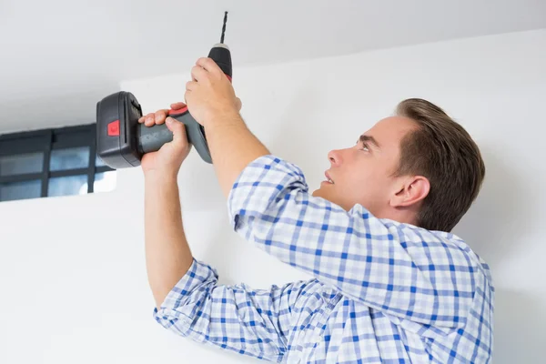 Handyman using a cordless drill to the ceiling — Stock Photo, Image