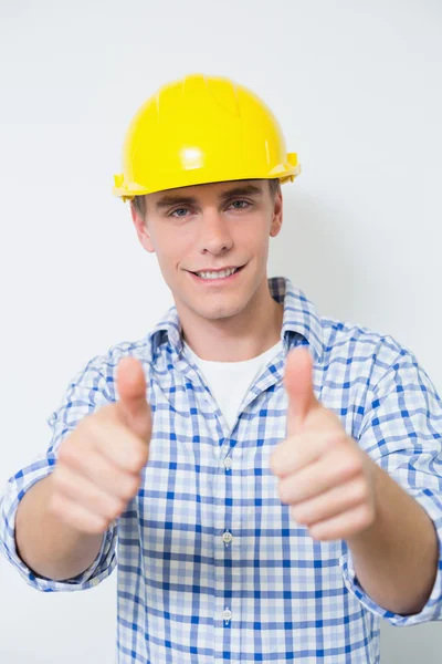 Smiling handyman em amarelo chapéu duro gesticulando polegares para cima — Fotografia de Stock