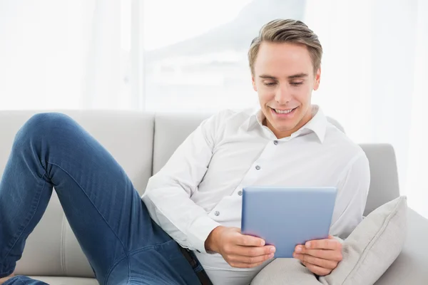 Hombre joven casual usando tableta digital en el sofá — Foto de Stock