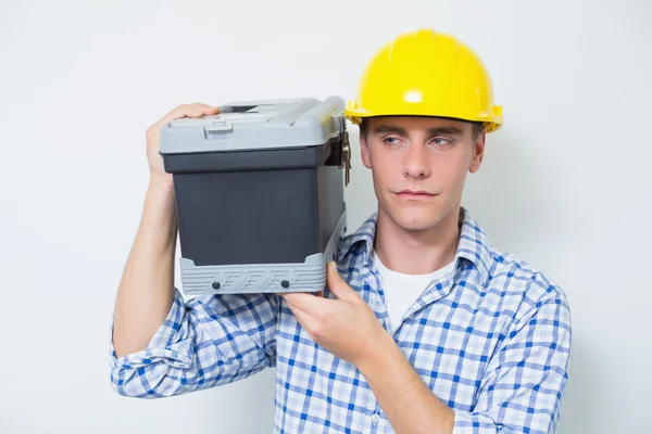 Serious handyman in yellow hard hat carrying toolbox — Stock Photo, Image