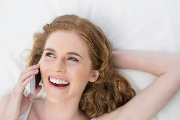 Neşeli kadın yatakta istimal hareket eden telefon — Stok fotoğraf