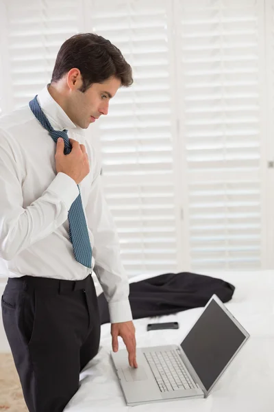 Empresario con corbata mientras usa el portátil en una habitación de hotel — Foto de Stock