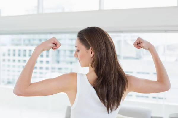 Fitte braunhaarige Frau lässt im Fitnessstudio die Muskeln spielen — Stockfoto