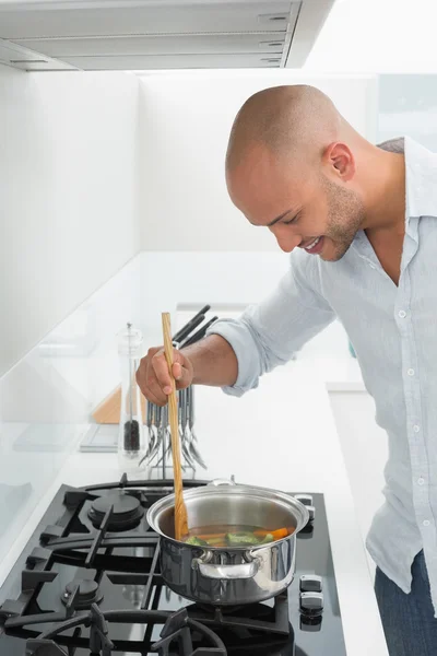 Jovem sorridente preparando comida na cozinha — Fotografia de Stock