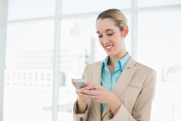 Zufriedene elegante Geschäftsfrau, die mit ihrem Smartphone SMS schreibt — Stockfoto