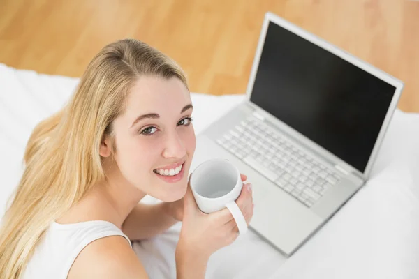 Mujer joven y tranquila acostada en su cama sosteniendo una taza —  Fotos de Stock